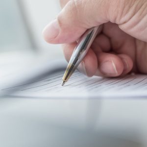 Person filling out a survey with a pen.
