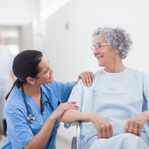 A nurse and patient smile at each other.