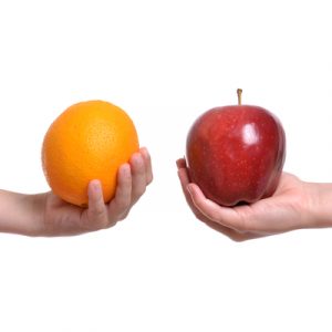 Two white children's hands, one holding an orange and one holding an apple, indicating the comparison between the Graham-Cassidy proposal and other acts.
