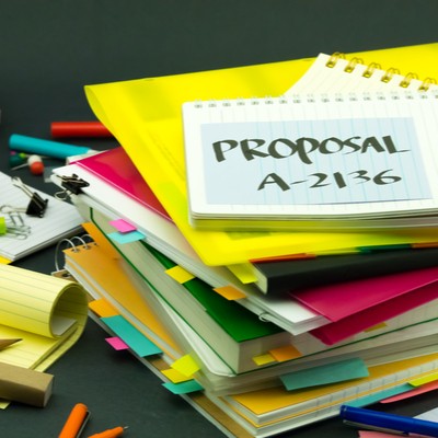 A stack of red and yellow files and notebooks. On the top notebook, 